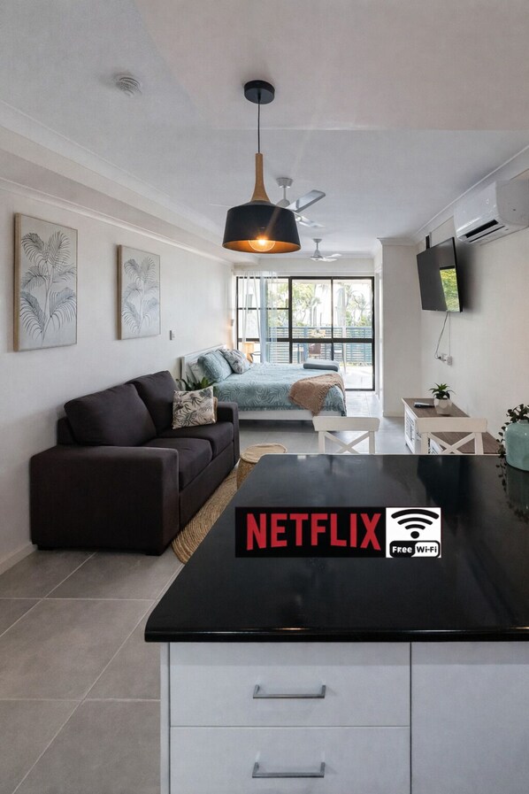 A modern living room with a sofa, a coffee table, and a TV mounted on the wall. - La Plage Cabane - stay by the Beach (Dolphin Heads)