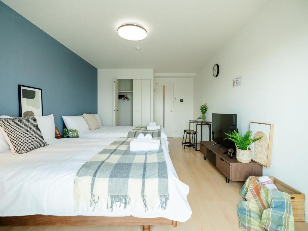 A modern hotel room with a large bed, a TV, a desk, and a wardrobe.