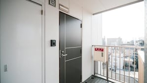 A modern elevator with a digital display, a door with a handle, and a small window with a view of the cityscape. - Chuan House Imazato (Osaka)