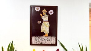 A room with a bench, potted plants, and a framed artwork on the wall. - Nishi Villa (Negombo)