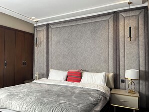 Ein modernes Schlafzimmer mit einem großen Bett, einem Nachttisch mit Lampe und einem Kleiderschrank.