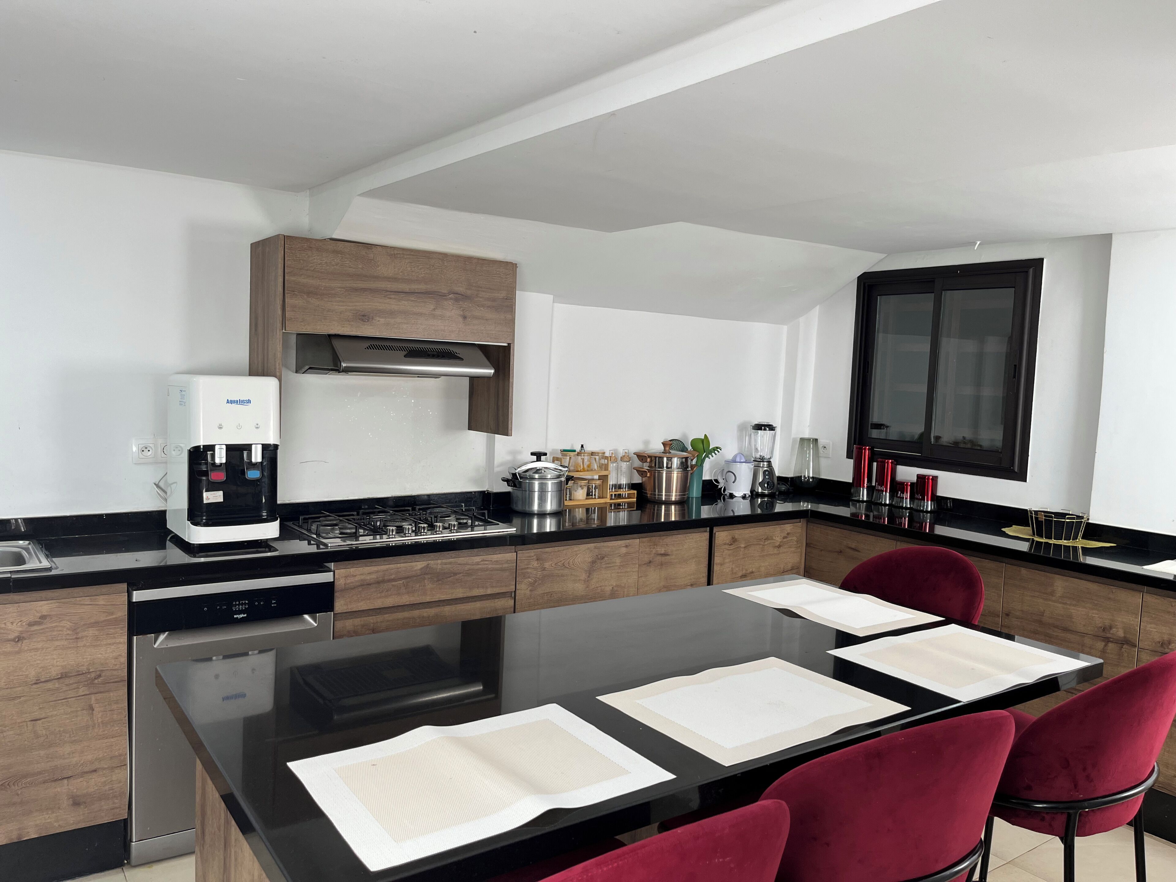 Une cuisine moderne équipée d’une cuisinière intégrée, d’une machine à café et d’un coin repas avec une table et des chaises.