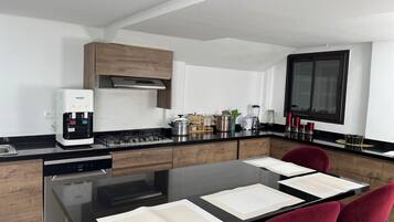 Une cuisine moderne équipée d’une cuisinière intégrée, d’une machine à café et d’un coin repas avec une table et des chaises.