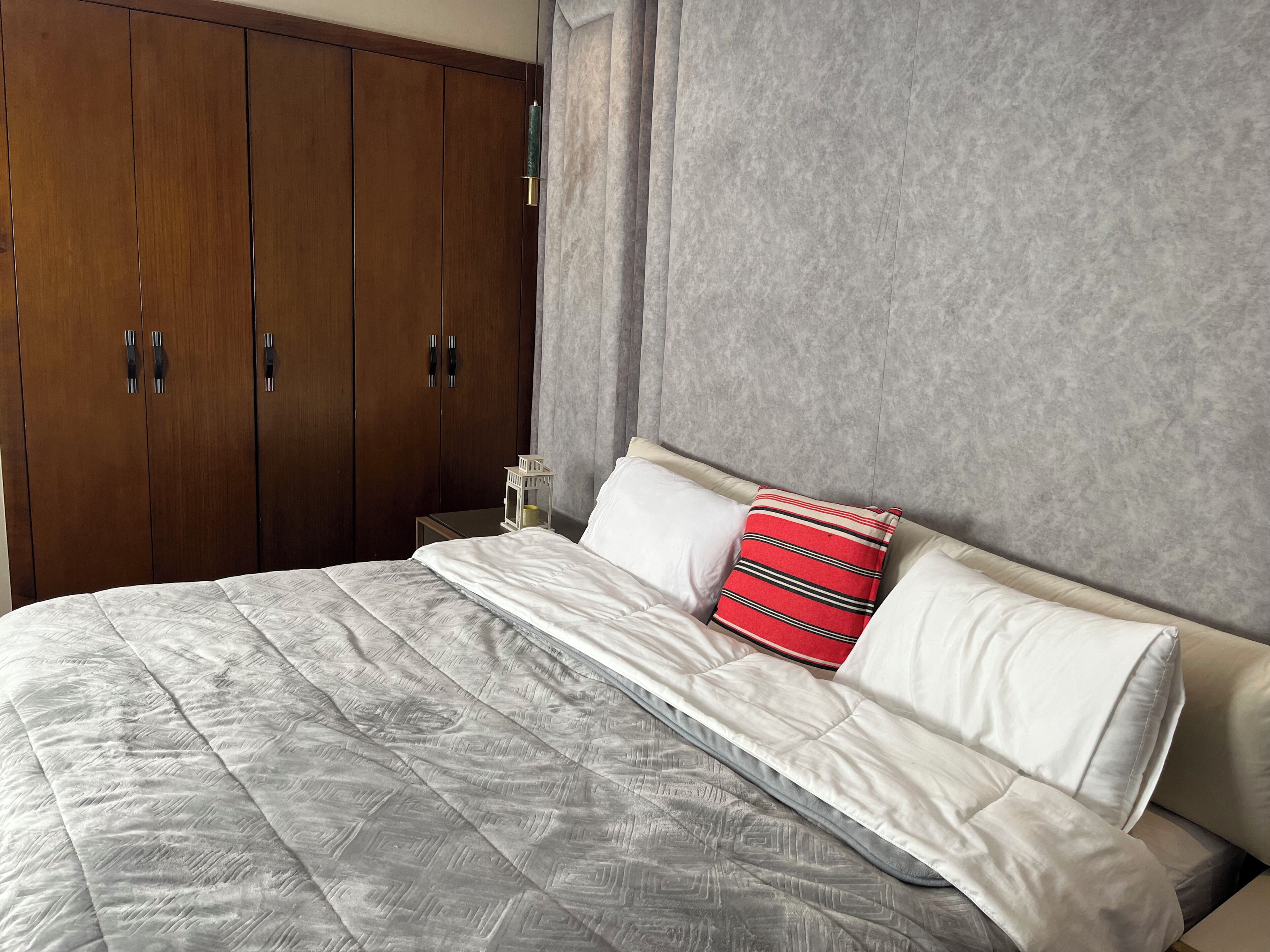 Een slaapkamer met een groot bed, een kledingkast en een nachtkastje.