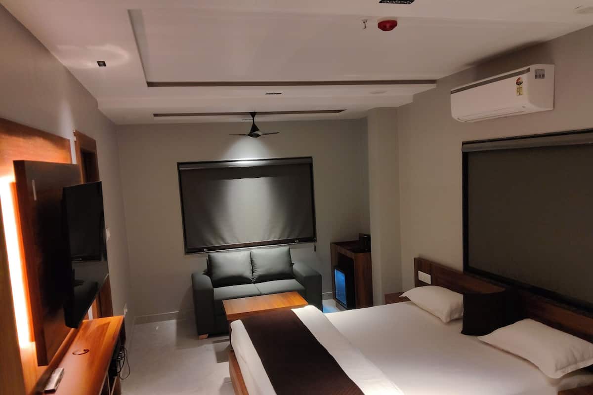 A modern hotel room with a large bed, a flat-screen TV, a ceiling fan, and an air conditioning unit.