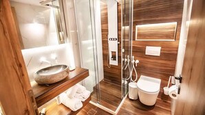 Un baño moderno con ducha de vidrio, tocador de madera, un espejo grande y un inodoro.