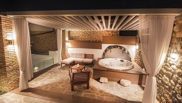 Un área de spa con jacuzzi, asientos y paredes de piedra.