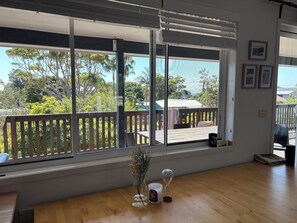 Een kamer met grote ramen, een houten tafel, een vaas met gedroogde planten en een zandloper.