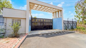 A gated entrance with a pergola, a small tree, and a paved driveway. - Classic Hotel Phoenix (Valappadi)