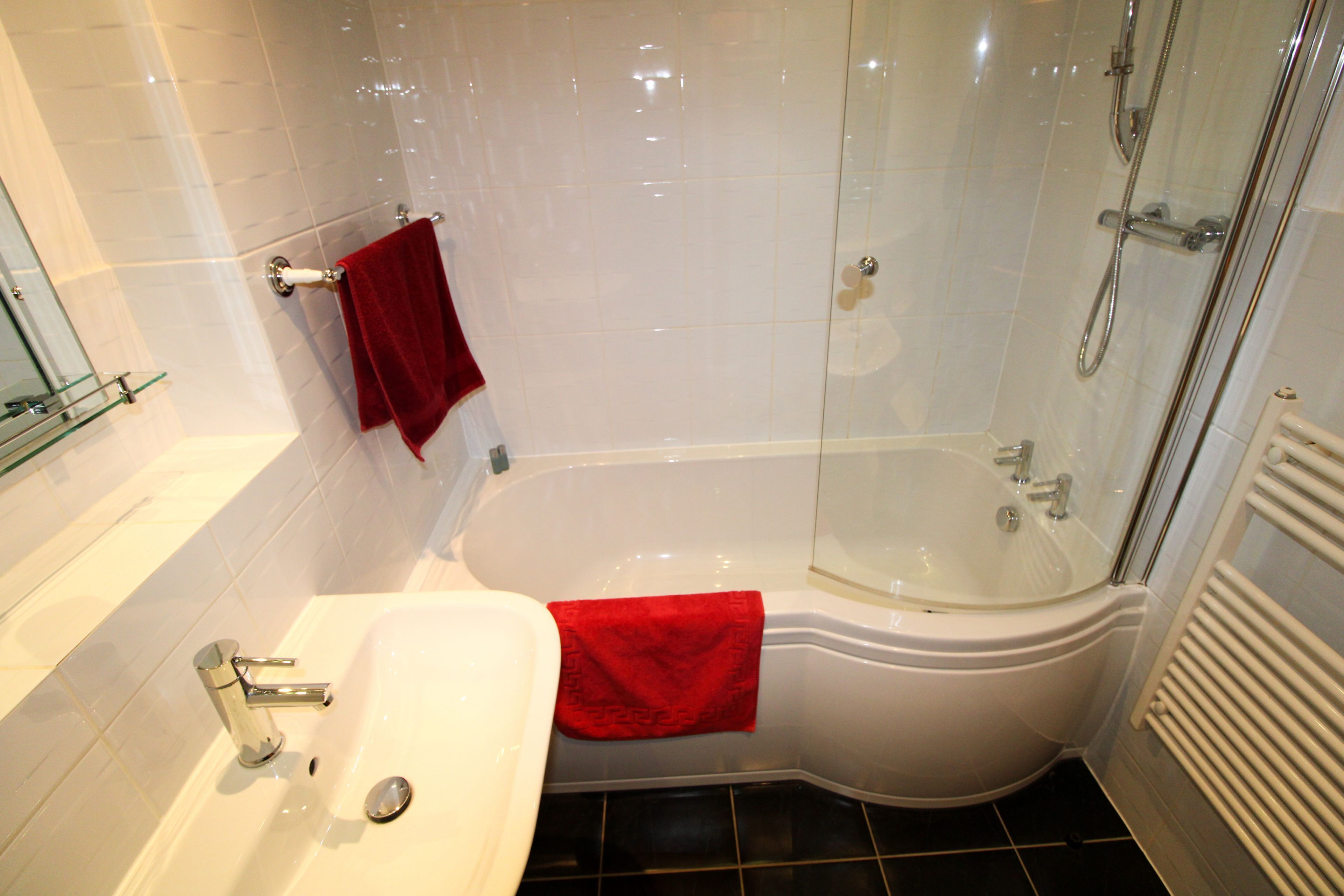 Ein Badezimmer mit einer Badewanne, einer Duschkabine und einem Waschbecken mit einem roten Handtuch.