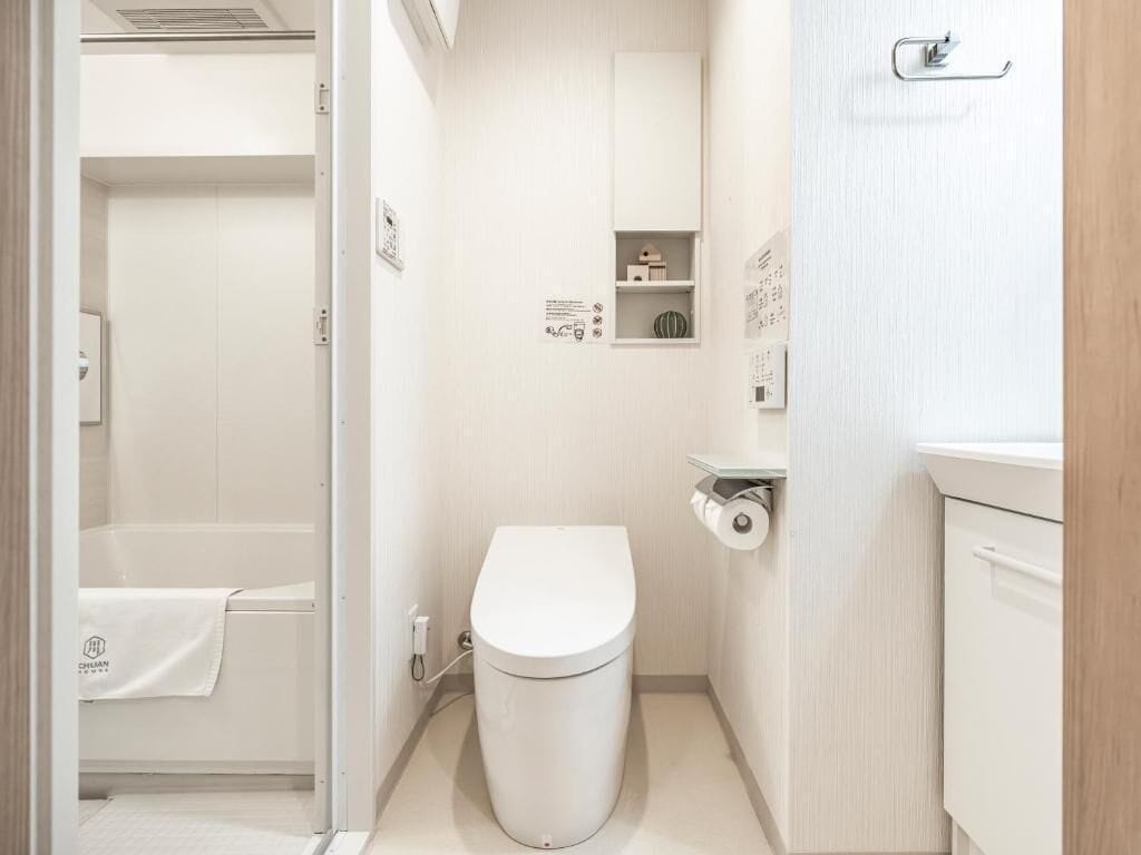 Ein kleines Badezimmer mit Toilette, einer kleinen Ablage für Toilettenartikel und einem Handtuchhalter.