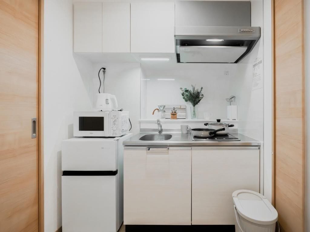 Una cocina pequeña con armarios blancos, un microondas, un lavaplatos y una estufa.