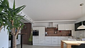 Eine moderne Küche mit weißen Schränken, einer Holzausziehtafel und einem Essbereich mit Tisch und Stühlen.