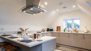 A modern kitchen with a central island, bar stools, and a window providing natural light. - Beautiful 2 Bedroom Apartment in Malvern (Malvern)