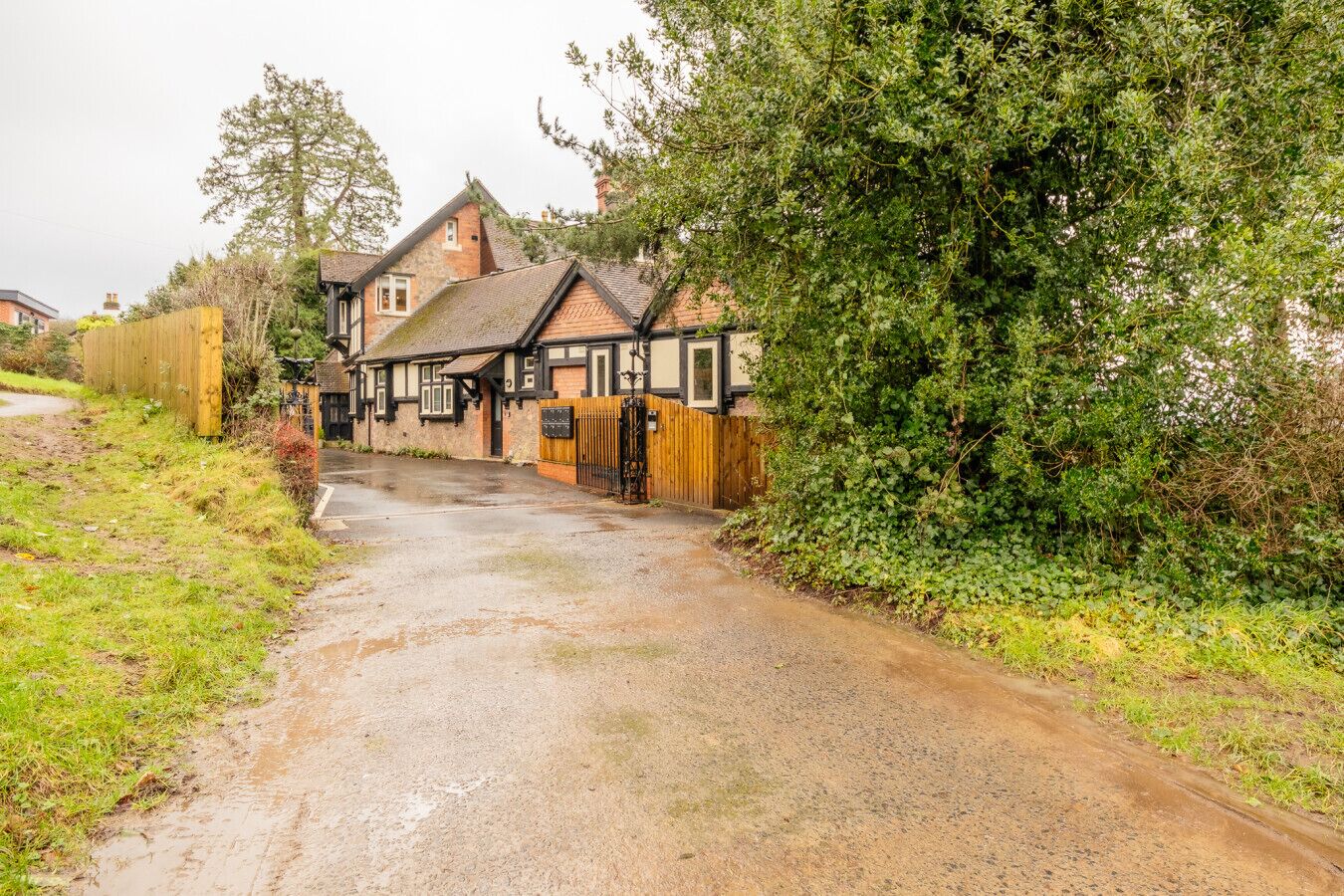 A traditional half-timbered building with a gravel driveway leading to a wooden gate.