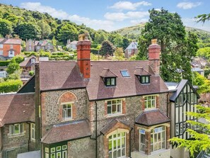 A traditional stone house with multiple chimneys, a sloped roof, and a bay window. - Beautiful 2 Bedroom Apartment in Malvern (Malvern)