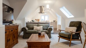 A cozy loft apartment with a dining area, a sofa, a wooden coffee table, and a chair. - Beautiful 2 Bedroom Apartment in Malvern (Malvern)