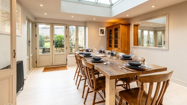A dining area with a large table set for six, wooden chairs, a wooden cabinet, and a skylight above. - Fleur de Lys - Beautiful Home in the Heart of Winchcombe (Winchcombe)