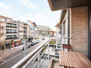 Ein Balkon mit Blick auf eine Stadtstraße, ein Backsteinhaus und ein Geschäft mit Kleidungsstücken.