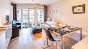 Ein modernes Apartment mit Essbereich, einer Couch und einem Fernseher.
