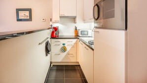 Eine moderne Küche mit weißen Schränken, einem Edelstahlbackofen, einer Mikrowelle und einer Kaffeemaschine.