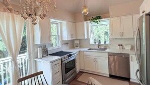 Una cucina moderna con mobili bianchi, un frigorifero in acciaio inossidabile e un lampadario.