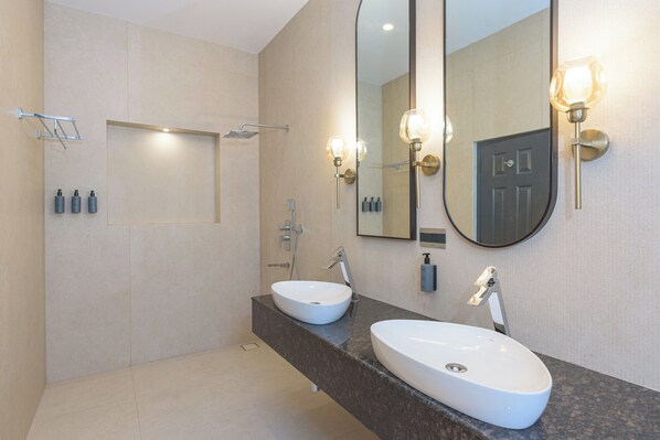 Une salle de bain moderne avec deux vasques, un grand miroir et des luminaires fixés au mur.