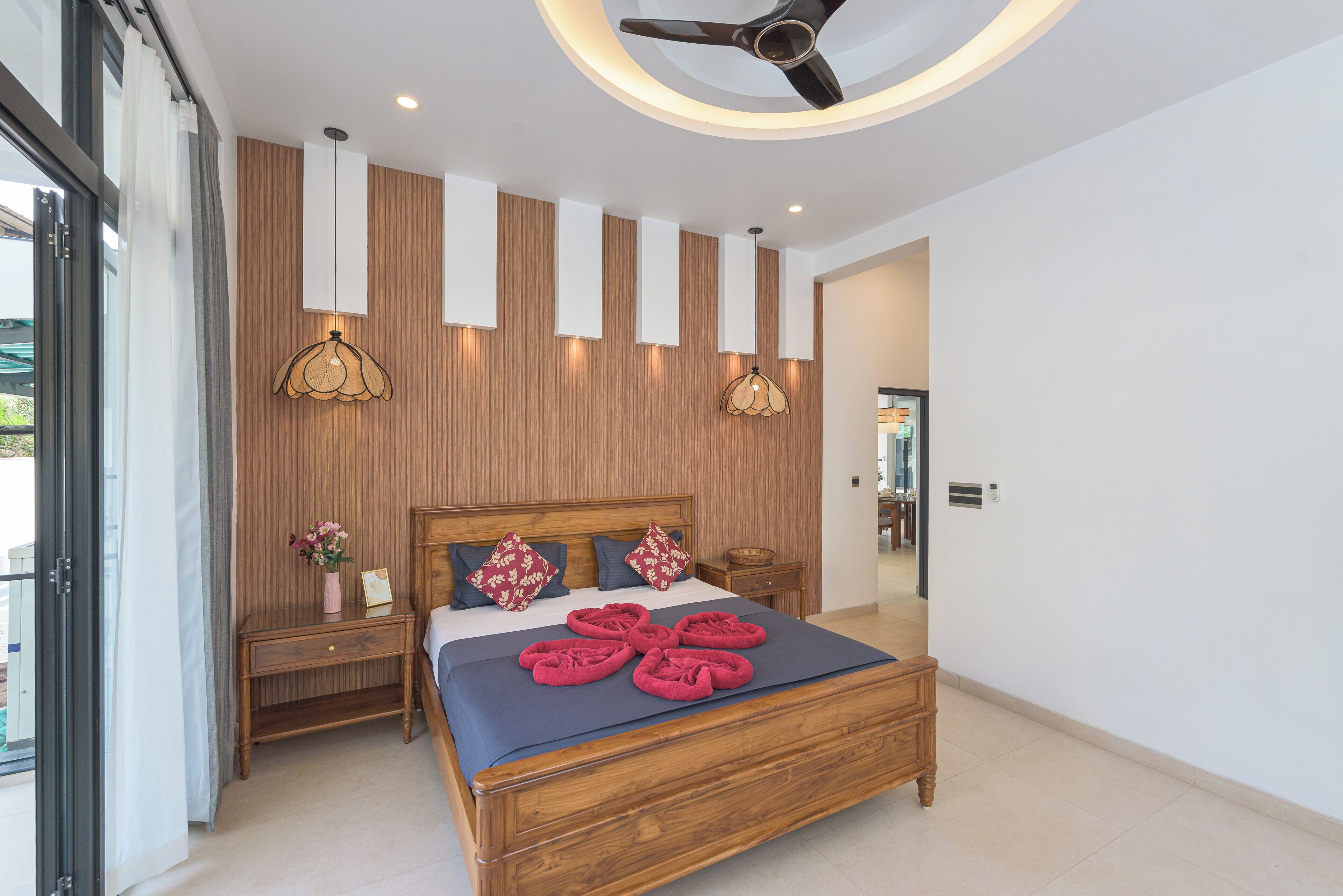 A modern bedroom with a wooden bed, bedside tables, and a ceiling fan.
