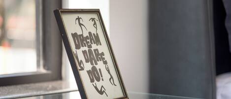 Uma placa emoldurada com o texto 'DREAM DO!' em uma superfície refletora.
