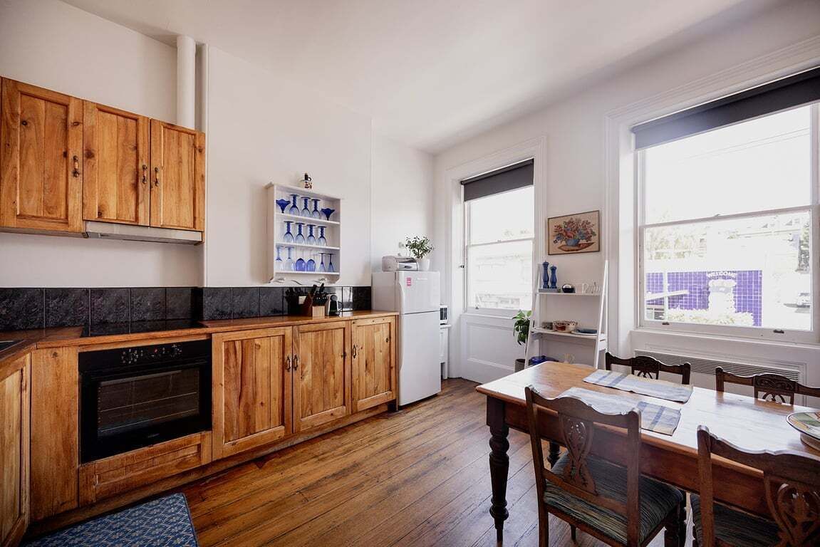 A kitchen with wooden cabinets, a black oven, and a dining area with a table and chairs.