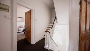 Eine Treppe mit Holzgeländern und Teppichboden, die zu einem Zimmer mit einem Bett und einem Spiegel an der Wand führt.
