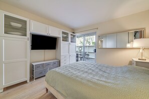 Un dormitorio con cama, televisor, cómoda y balcón con mesa y sillas.