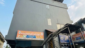 A building with a sign for Krishna Hotel, featuring a contact number and a list of dishes. - Townhouse Guwahati Airport (Guwahati)