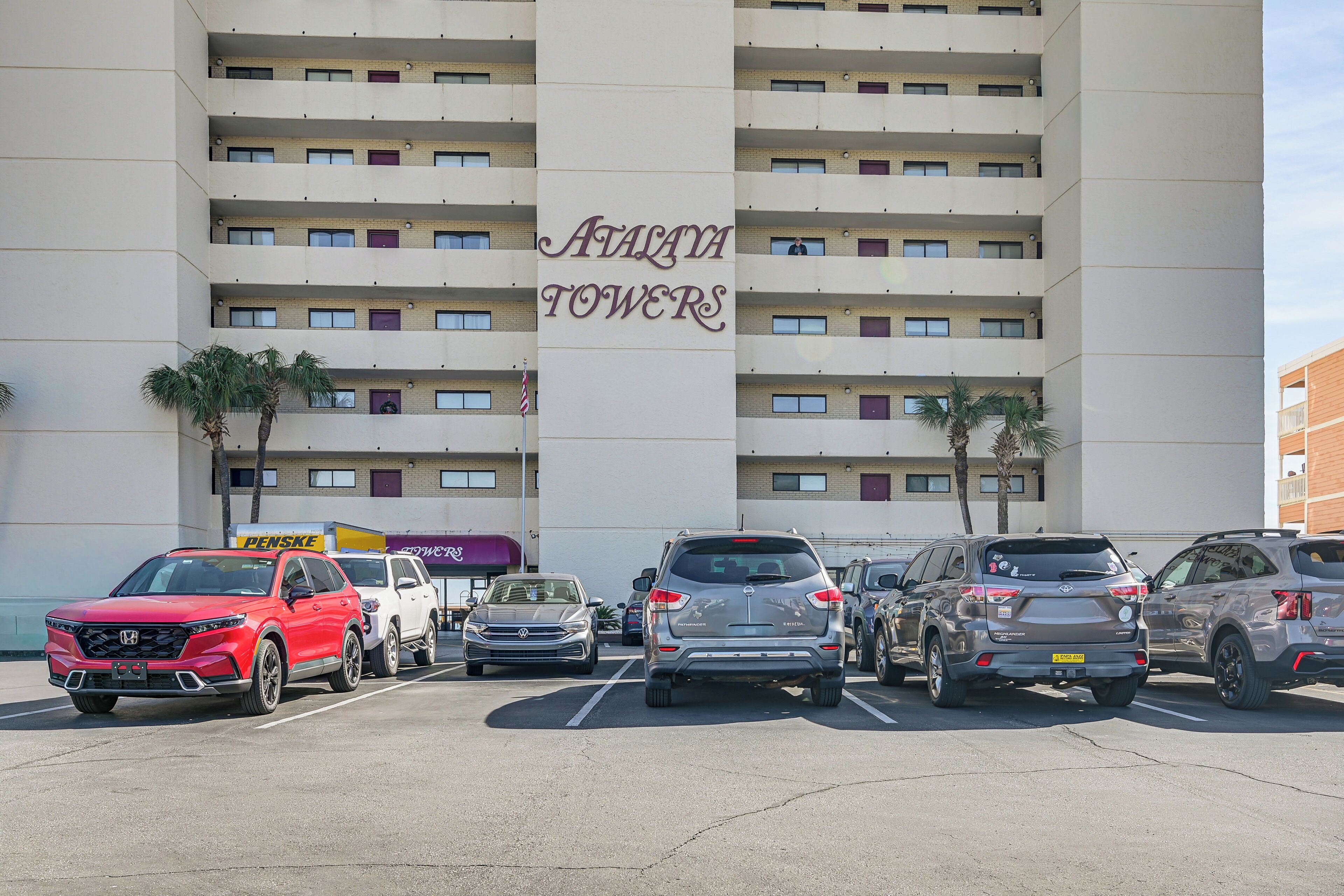 A parking lot with several SUVs parked in front of a building labeled "Avasaya Towers".