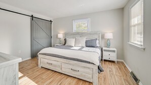 Een slaapkamer met een bed, twee nachtkastjes, een raam en een schuifdeur.