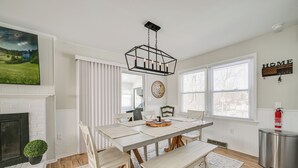 Een eetkamer met een witte tafel, banken en een hangende lamp.