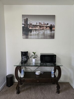A glass-top coffee table with a microwave and a coffee maker, a potted plant, and a water bottle. - Private Guest Suite + Pool Access, North Hanford (Hanford)