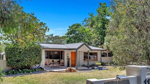 A modern house with a large glass door, a small porch, and a well-maintained garden.