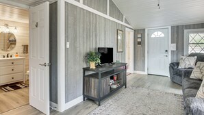 Ein Wohnzimmer mit einem dunklen Holz-Entertainment-Möbel, einem grauen Sofa und einem gemusterten Teppich.