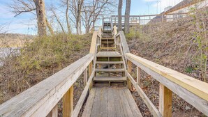 Eine Holztreppe führt zu einer Brücke, umgeben von Bäumen und dichter Vegetation.