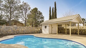Piscina com parede de pedra e área de varanda coberta.