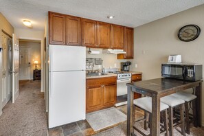 A kitchen with wooden cabinets, a refrigerator, stove, microwave, and a dining table with chairs. - Resort Perks! Waterfront Lake of the Ozarks Gem (Osage Beach)