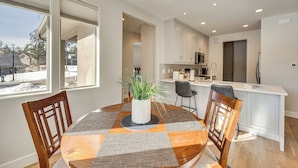 Een moderne keuken met witte kasten, een centraal eiland en een eethoek met een ronde tafel en stoelen.
