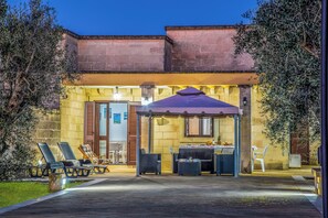 A building with a patio area featuring outdoor seating and a covered table. - Villa Gloria and Marta With Garden Near The Sea (Melendugno)