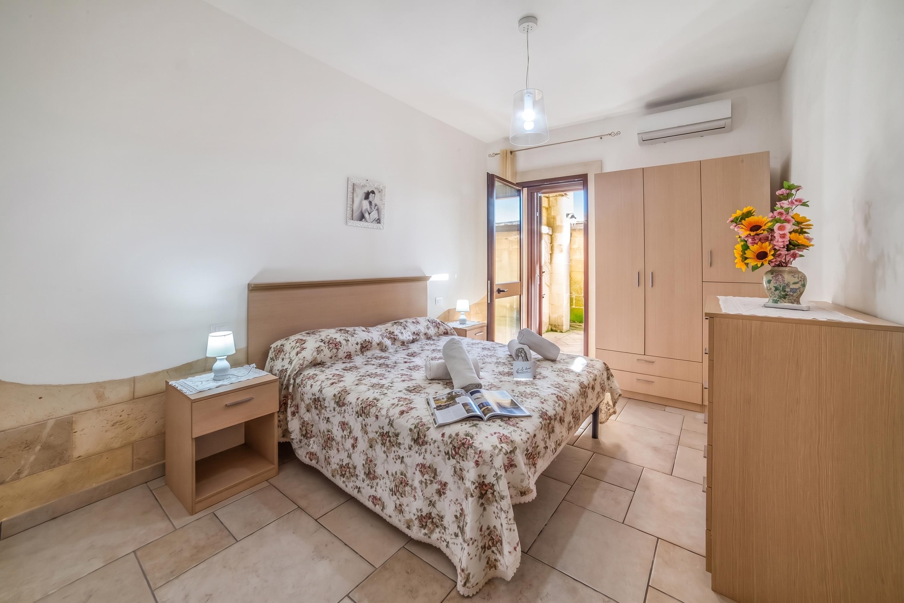 Ein Schlafzimmer mit einem Bett, Nachttischen, einem Kleiderschrank und einer Klimaanlage.