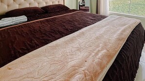 A bedroom with a large bed, a headboard, a mirror, and a window with curtains. - Homestay Gavilla Dieng (Kejajar)