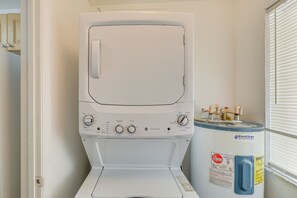 Un appareil combiné lave-linge et sèche-linge à chargement frontal, doté de boutons de commande et d’un réservoir d’eau.