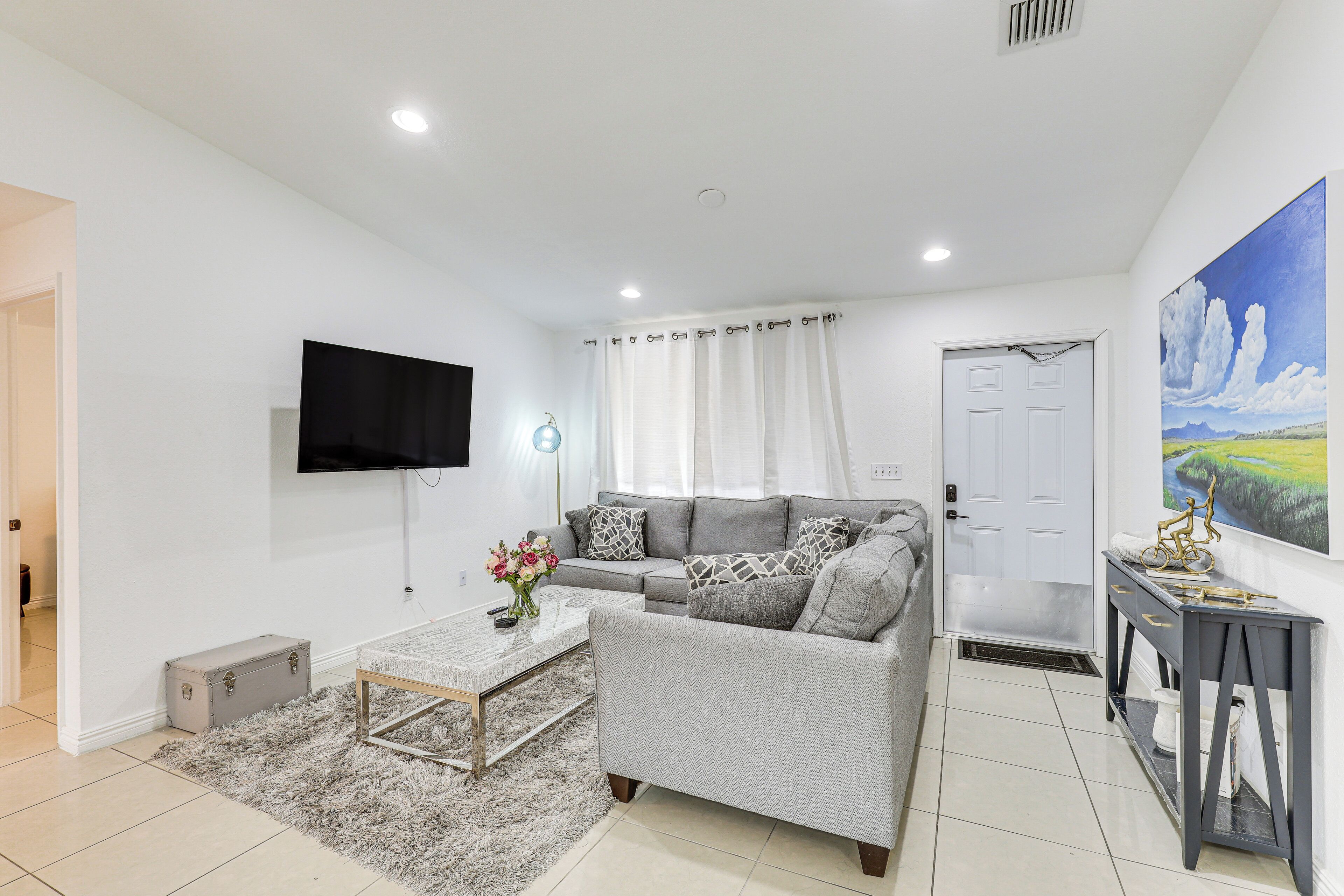 A modern living room with a grey sofa, a coffee table, and a TV mounted on the wall.