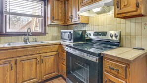 A kitchen with wooden cabinets, a stove, a microwave, and a sink. - Pet Friendly & WFH Ready! Quiet Hudson Valley Apt (Newburgh)
