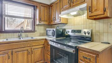 A kitchen with wooden cabinets, a stove, a microwave, and a sink.